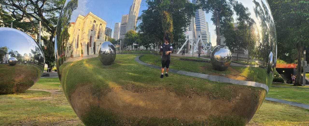 Chrome spheres on a lawn, reflecting a person, trees, and the towers behind the National Museum.