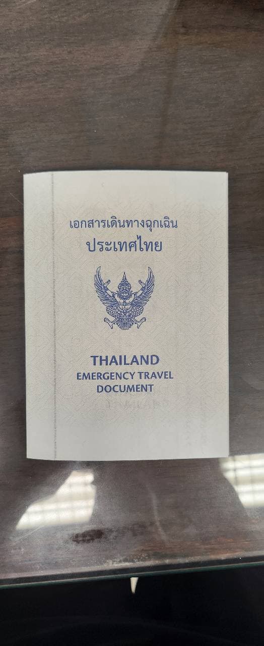 The cover of a Thailand Emergency Travel Document, with the Garuda emblem, lying on a dark table. Can't believe this tiny piece of paper can take me home. Passport loser be like.